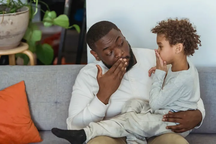 Ein Vater und sein Kind lachen zusammen auf einem Sofa