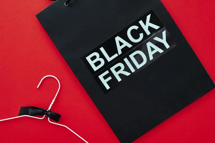 Eine schwarze Geschenktüte mit der Aufschrift Black Friday vor rotem Hintergrund