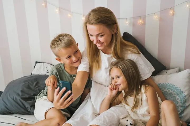Eine Mutter lächelt mit ihren zwei Kindern zu Hause