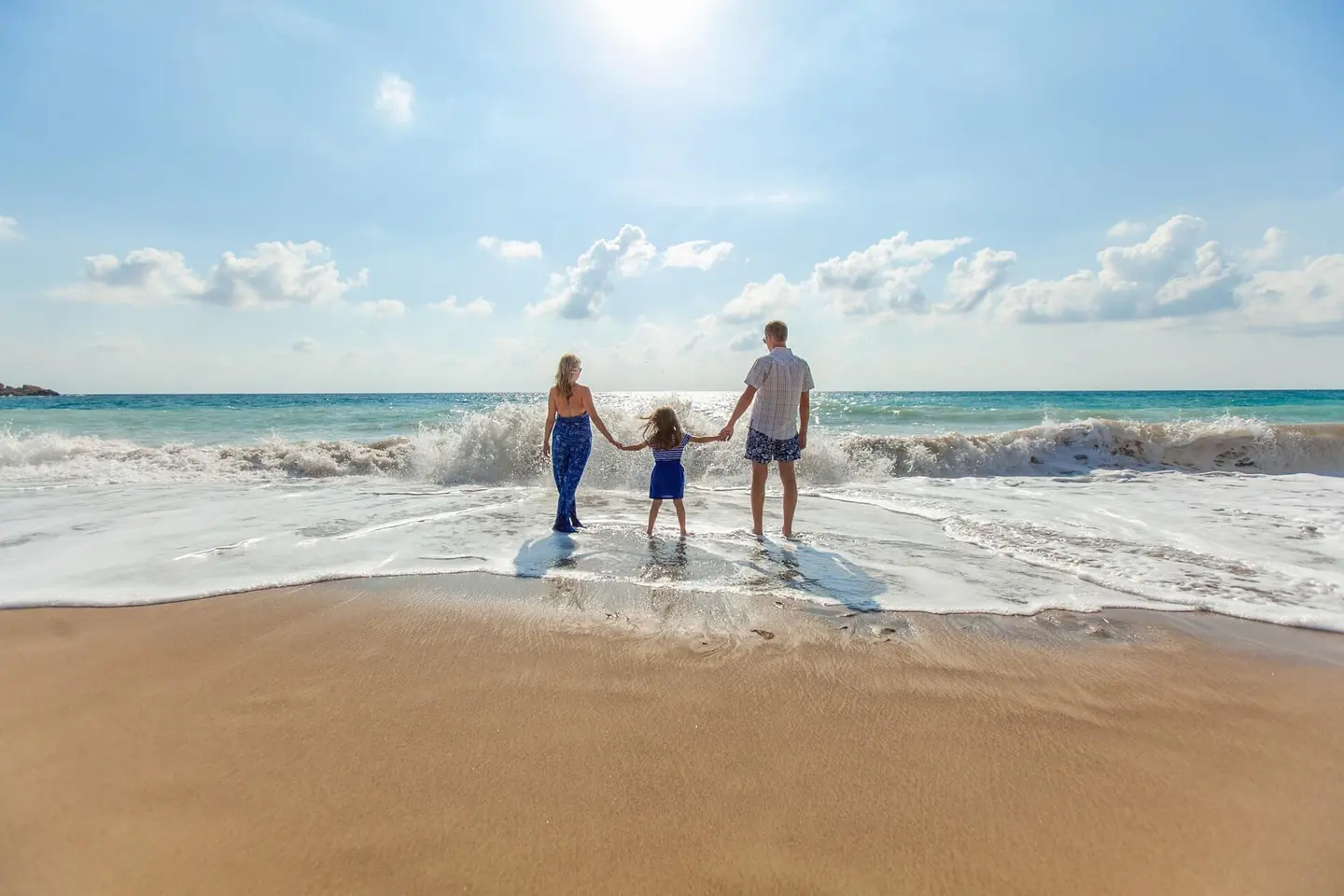 Family holding hands at the edge of the ocean